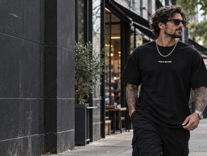 Hombre con polera oversize negra Cold Blood caminando por la ciudad